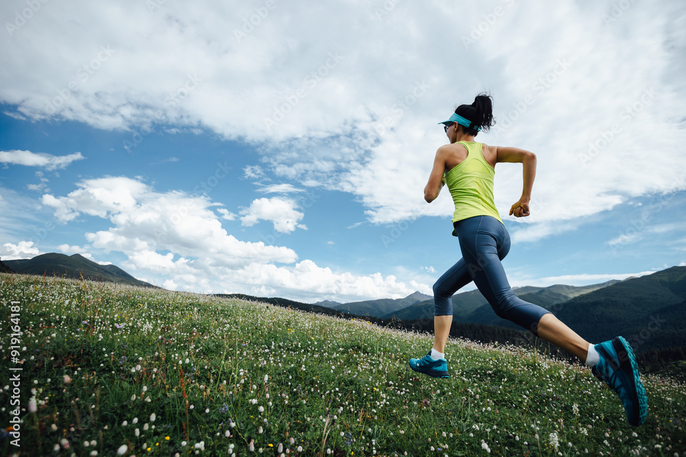 Fitness woman runner running at flowering grassland mountain top Fitness woman runner running at flowering grassland mountain top