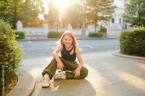 Stylish kid girl with blonde pink hairstyle pre teen age 9 -10 year old wearing trendy top and cargo pants over city street outdoor. Childhood photo