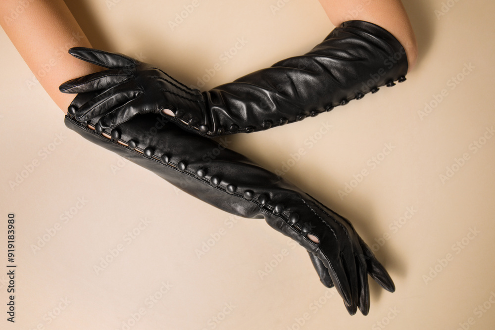 Female hands in long black gloves on a beige background