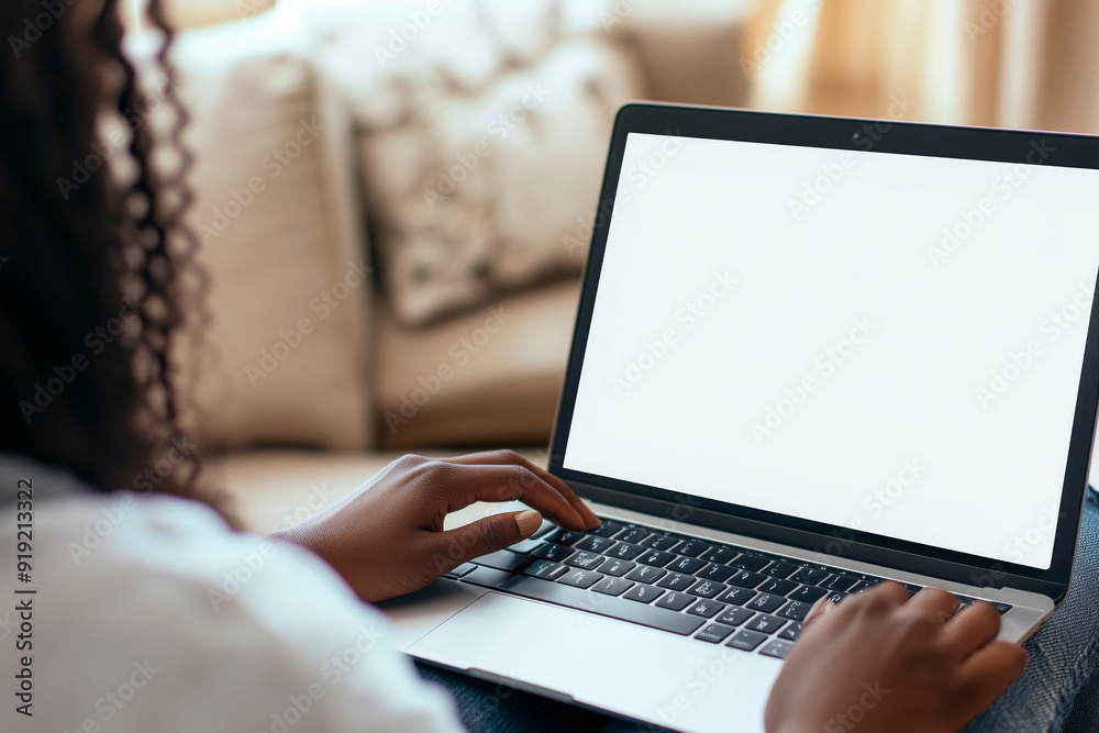 Close-up view of a person using a laptop with a blank white screen, seated in a cozy home environment.
Close-up view of a person using a laptop with a blank white screen, seated in a cozy home environment.