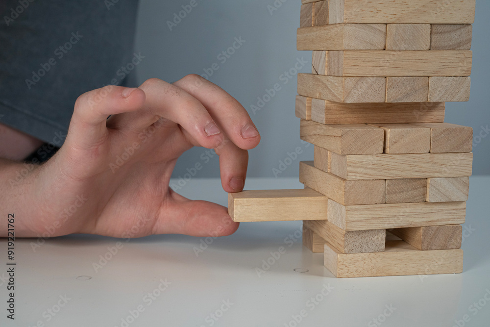 Gra jenga, usuwanie pojedynczych klocków drewnianych z bloku.