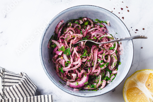 Turkish sumac onion salad in gray bowl, white background.