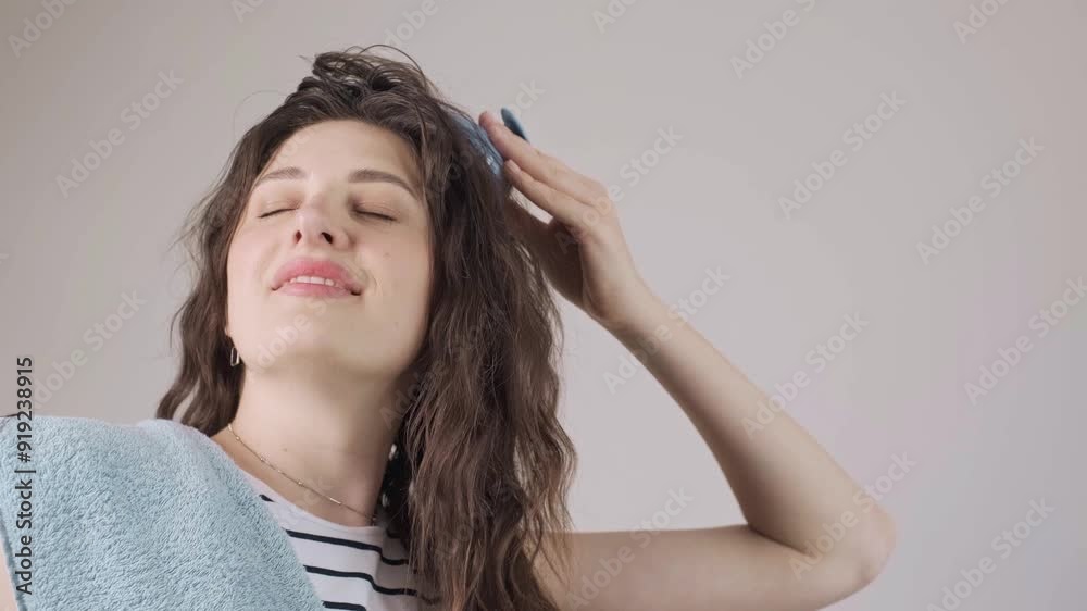 Portrait of a beautiful young girl with long dark hair, applying hair growth oil with a pipette, and massaging her scalp with a brush. Portrait of a beautiful young girl with long dark hair, applying hair growth oil with a pipette, and massaging her scalp with a brush.