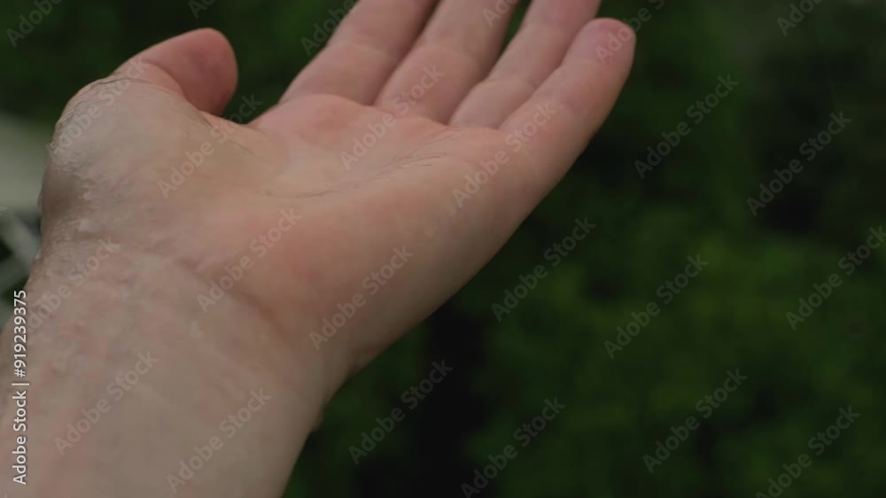 A slow motion shot of rainwater splashing onto an unrecognizable palm. A slow motion shot of rainwater splashing onto an unrecognizable palm.