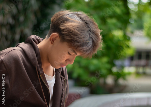 Asian teenboy in a brown shirt sits lonely in a juvenile detention community center, awaiting further release, depression,freedom and detention of young people concept. photo