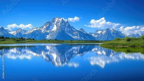 Majestic snow-capped mountain range with a clear lake reflection under a bright blue sky, symbolizing tranquility and natural beauty