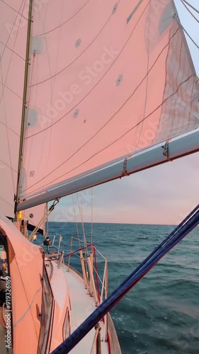 Luxury cruise on a sailing rigged yacht under a genoa and mainsail sailing in a light wind and sunset light during the regatta. Yachting as a luxury sport and great vacation. View from the deck to the