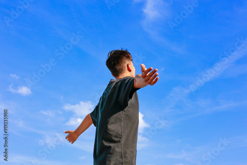 Canvastavla Young teenager boy with arms outstretched breathing in fresh air against blue sky
