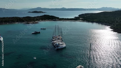 Beautiful aerial drone shot of sailboats anchored together in tropical blue water bay off the coast of Sardinia. vacation, sailing, boats.