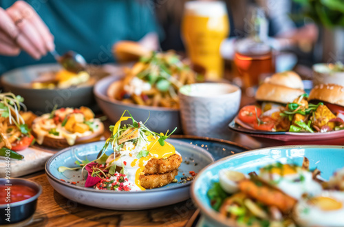 Inviting Brunch Spread with Eggs Benedict and Sides. A colorful and delicious array of brunch dishes, including eggs benedict and fresh greens, served in a lively dining setting. 