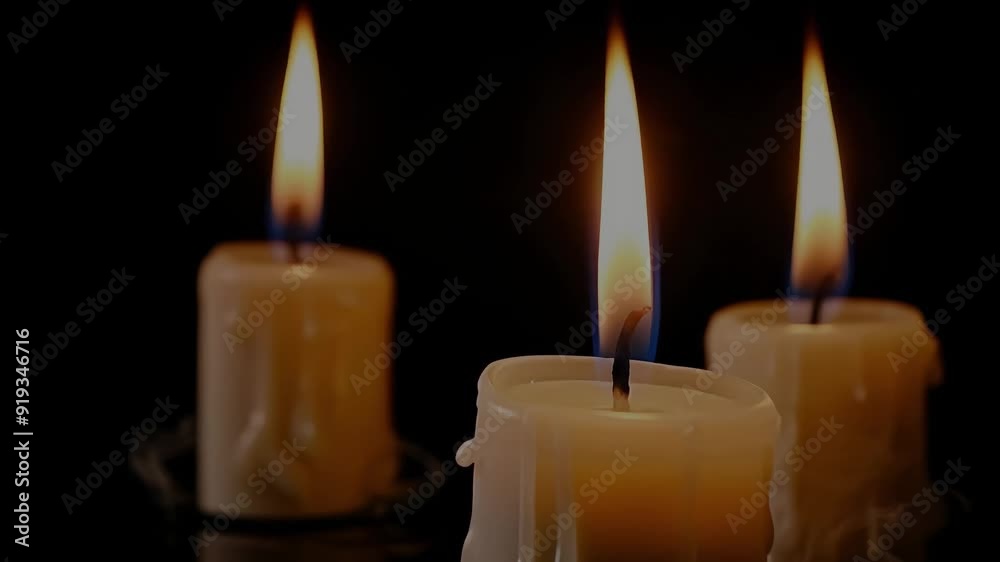 Two melting wax candles with flames burning in dark background. Two melting wax candles with flames burning in dark background.