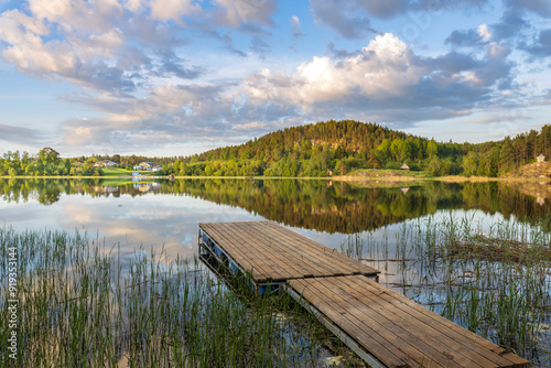 Fototapeta Naklejka Na Ścianę i Meble -  A dock is on a lake with a cloudy sky in the background