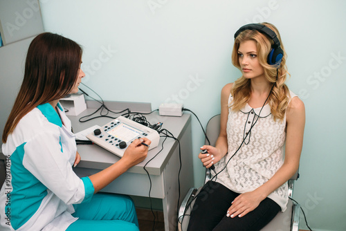 Hearing test in a clinic with a young woman undergoing audiometry photo