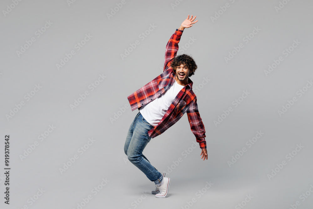 © ViDi Studio - Full body side profile view young happy smiling Indian man wearing red shirt casual clothes stand on toes lean back with outstretched hands isolated on plain grey color background. Lifestyle concept. © ViDi Studio - Full body side profile view young happy smiling Indian man wearing red shirt casual clothes stand on toes lean back with outstretched hands isolated on plain grey color background. Lifestyle concept.