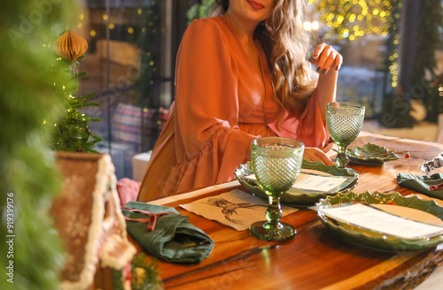 Happy pregnant woman in a pink dress sitting at the festive table. Holiday atmosphere. New Year.