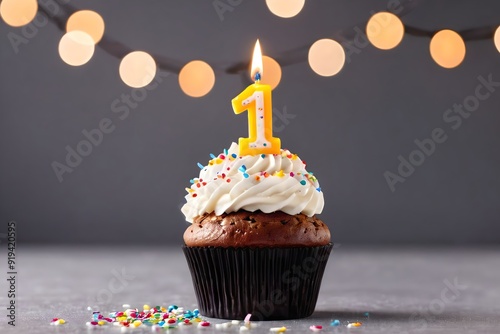 1st birthday cupcake with whipped cream, sprinkles, candles, and number 1, isolated on dark background with bokeh lights