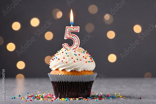 5th birthday cupcake with whipped cream, sprinkles, candles, and number 5, isolated on dark background with bokeh lights