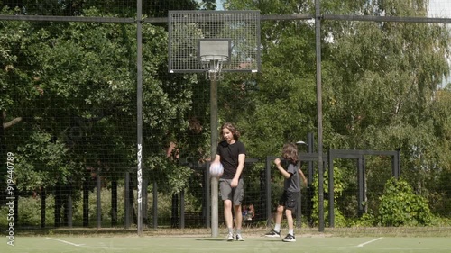 Friends alternate shots at the basketball hoop, mixing success and failure. The ball rebounds off the rim as they keep practicing, balancing fun with effort and the challenge of improvement. photo