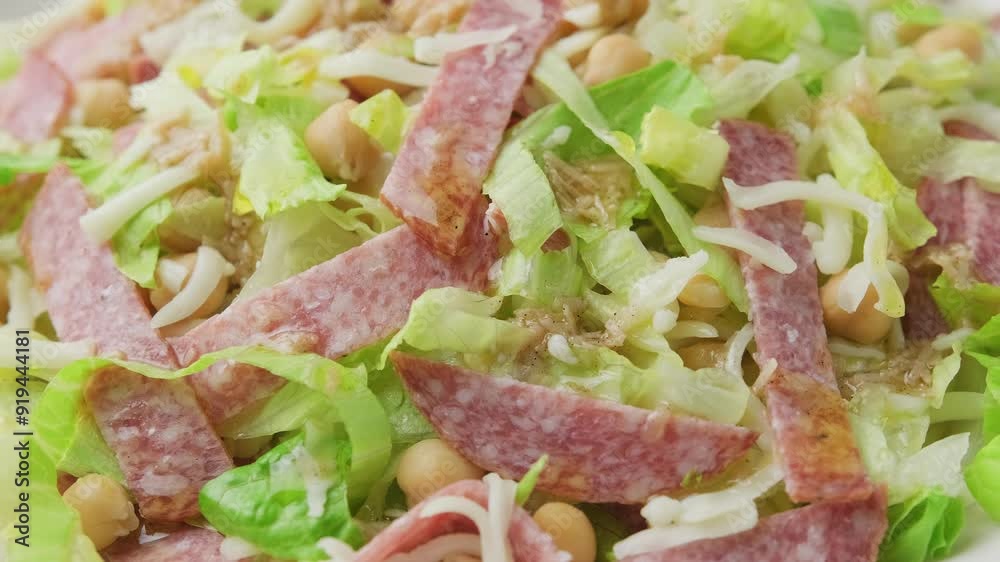 La Scala Salad with romaine lettuce, salami, mozzarella cheese and chickpeas in white plate. Rotating video La Scala Salad with romaine lettuce, salami, mozzarella cheese and chickpeas in white plate. Rotating video