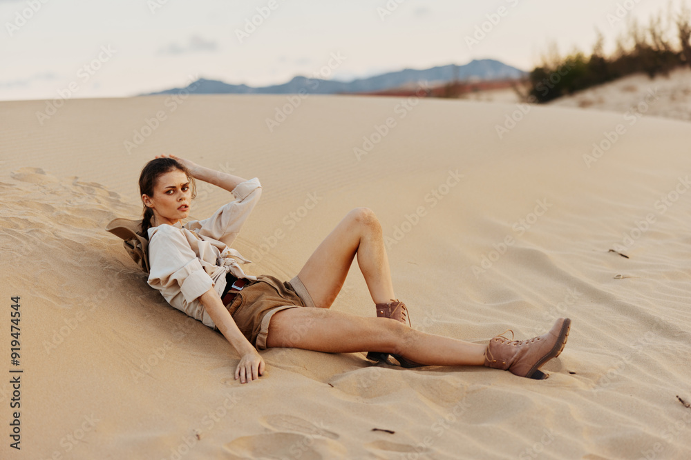 Lonely woman resting on a sand dune in the middle of the vast desert landscape Lonely woman resting on a sand dune in the middle of the vast desert landscape