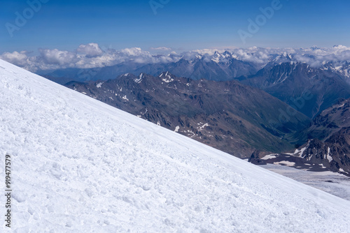 mountain landscape, view from highland icefield on slope to mountain ranges in the clouds, view from the Mount Elbrus to the Main Caucasian Range photo