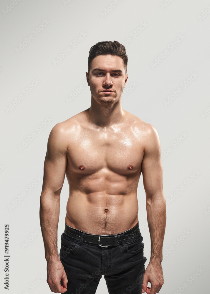 Portrait of a young, muscular man standing confidently without a shirt. He exudes strength, fitness, and determination, ideal for health and fitness themes. Portrait of a young, muscular man standing confidently without a shirt. He exudes strength, fitness, and determination, ideal for health and fitness themes.