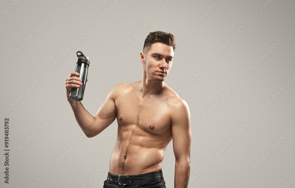 Shirtless fit man posing confidently with a water bottle. Health, fitness, and hydration concept captured in a studio setting. Shirtless fit man posing confidently with a water bottle. Health, fitness, and hydration concept captured in a studio setting.