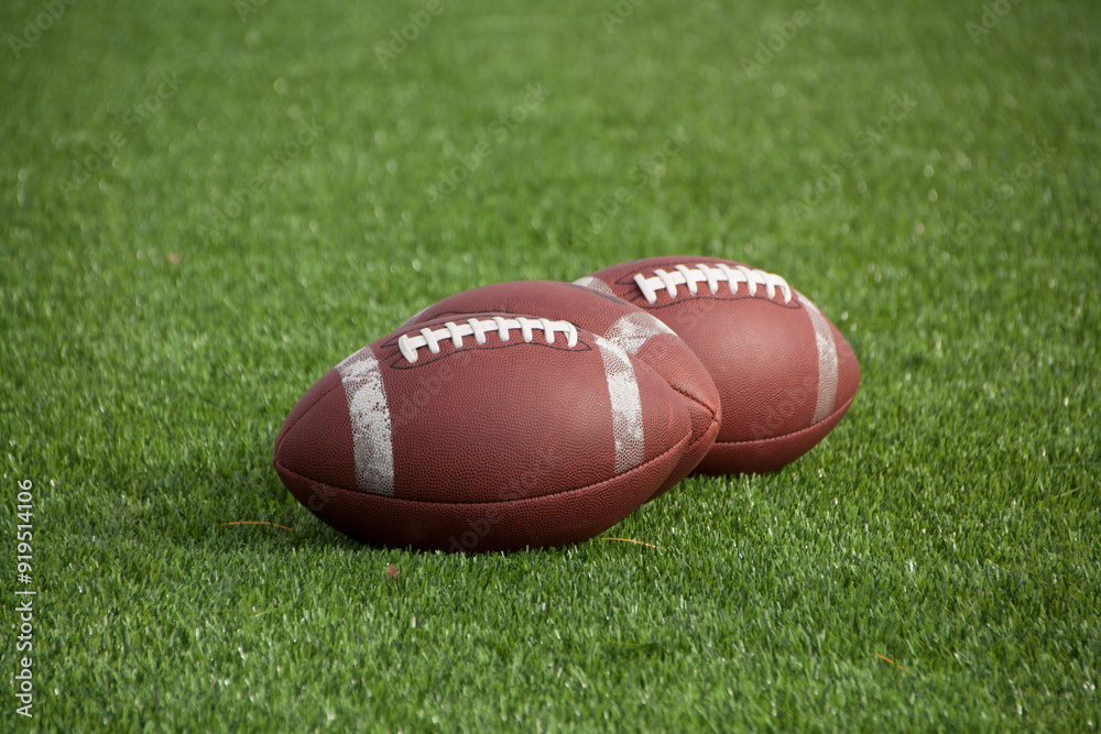 American footballs resting on the grass, ready for action, capturing the anticipation and spirit of the game before kickoff. American footballs resting on the grass, ready for action, capturing the anticipation and spirit of the game before kickoff.