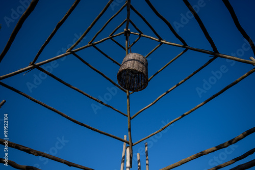 Wooden overhead structure with hanging light in a basket with blue sky background