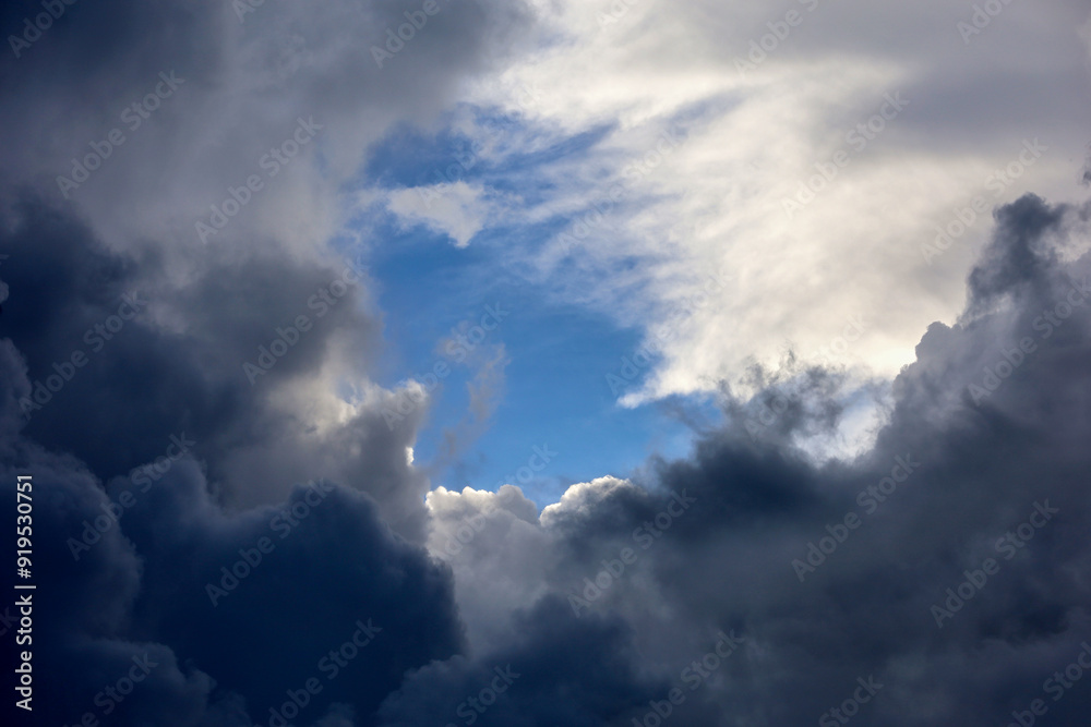 Obraz premium Sky with break into dark storm and white clouds. Dramatic background for weather before rain