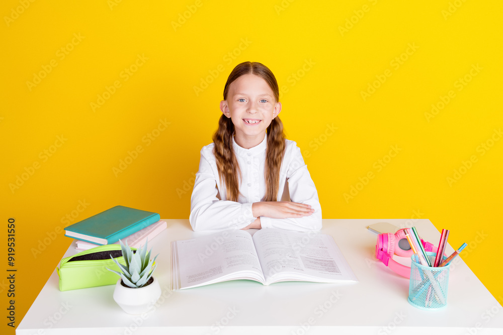 Photo portrait of cute little schoolgirl diligent sit table dressed stylish uniform isolated on yellow color background Photo portrait of cute little schoolgirl diligent sit table dressed stylish uniform isolated on yellow color background