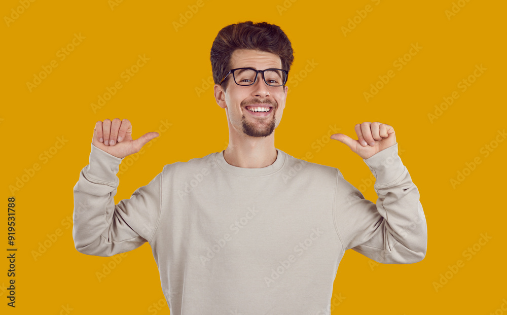 Smiling laughing brunet happy bearded man in beige sweatshirt and glasses pointing thumbs to himself isolated on yellow background. Banner for advertisement, marketing. Sincere human emotions concept. Smiling laughing brunet happy bearded man in beige sweatshirt and glasses pointing thumbs to himself isolated on yellow background. Banner for advertisement, marketing. Sincere human emotions concept.