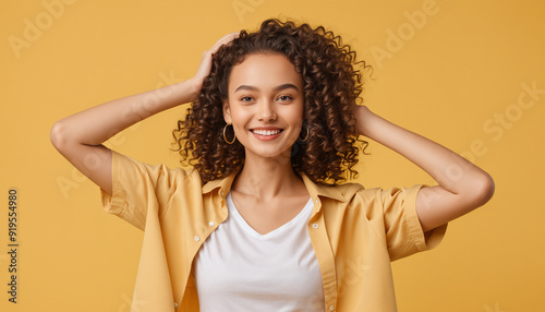 Femme modèle souriante cheveux bouclés fond jaune.