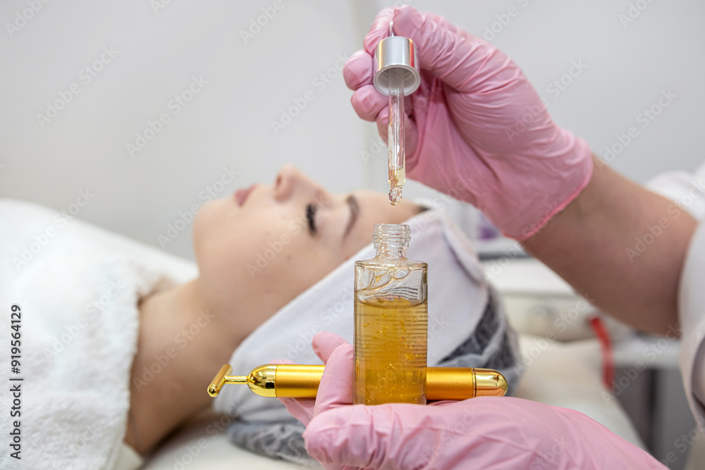Fototapeta premium closeup of beauticians hands is putting few drops essential oil with a pipette on the face women