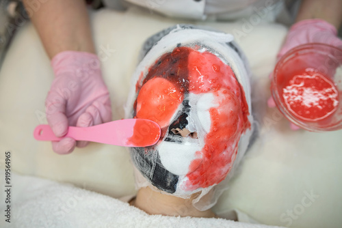 Cosmetologist doing procedure with alginate mask for anti-aging treatment face her female client photo