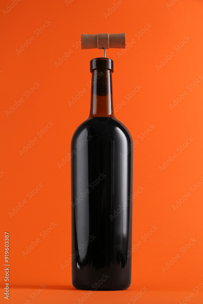 Wine bottle with corkscrew on orange background Wine bottle with corkscrew on orange background