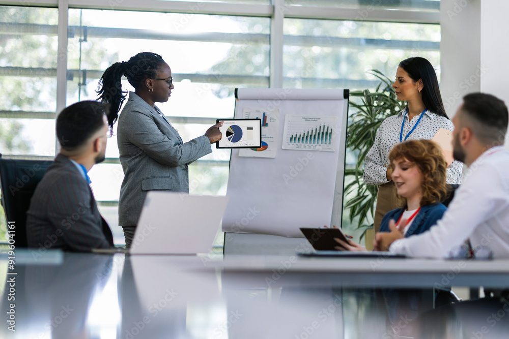 Two businesswoman talking on a meeting in an office with other colleagues. Showing graphics, diagrams and statistics. Two businesswoman talking on a meeting in an office with other colleagues. Showing graphics, diagrams and statistics.