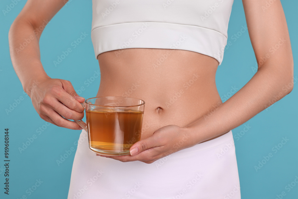 Weight loss concept. Woman with cup of diet tea on light blue background, closeup Weight loss concept. Woman with cup of diet tea on light blue background, closeup