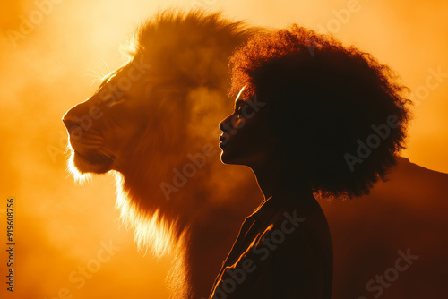 Profile of an African Woman with Natural Hair Facing a Lion in a Radiant Orange Glow, Symbolizing Inner Strength photo