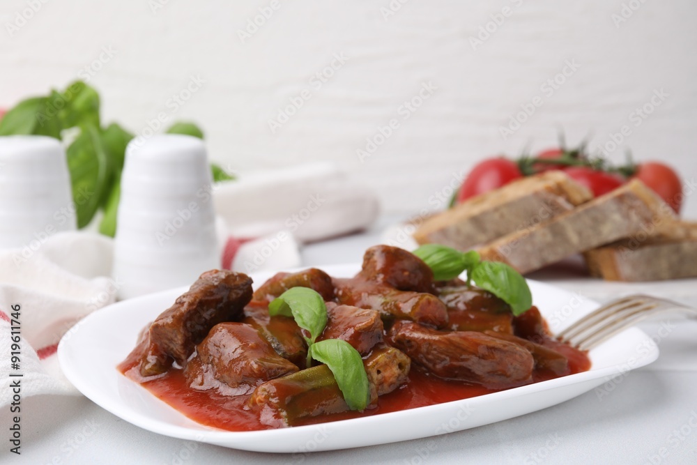 Tasty stew with okra, tomato sauce, bread and basil on white tiled table, closeup Tasty stew with okra, tomato sauce, bread and basil on white tiled table, closeup