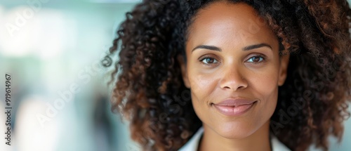  A tight shot of a woman in a white shirt and black tie, her curly hair framing a smiling face