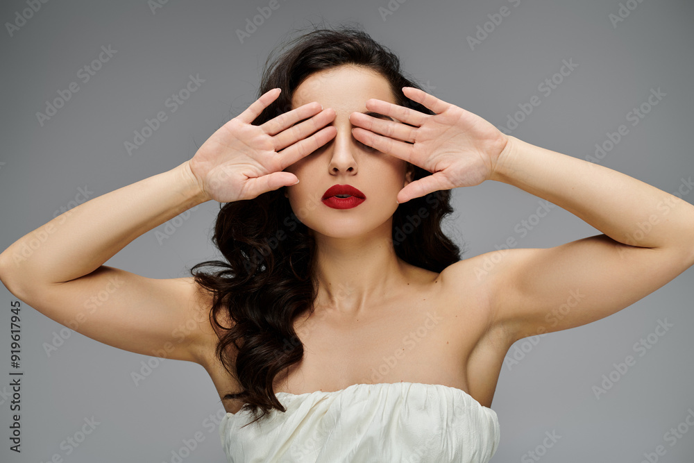 Chic woman poses gracefully on gray backdrop. Chic woman poses gracefully on gray backdrop.
