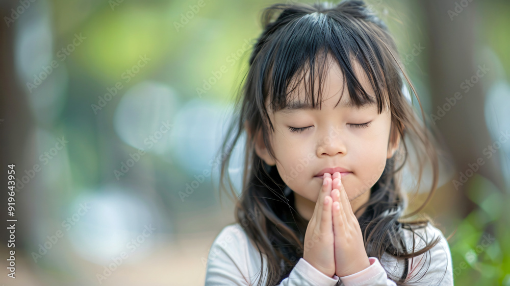 Praying young girl with closed eyes and clasped hands