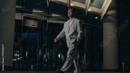 Wallpaper Mural Full length slowmo shot of Caucasian handsome man in oversized grey suit walking along expensive hotel building exterior at night, directing to event for celebrities and businessmen Torontodigital.ca