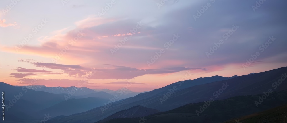 A mountain range backdrop with a pink-blue sky and clouds in the foreground A mountain range backdrop with a pink-blue sky and clouds in the foreground