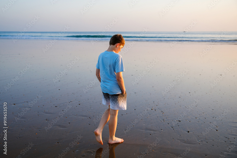 Happy cheerful teenager standing on beach at sunset. happy preteen boy smiling at the camera. Kid on family vacation at the ocean in Spain, costa del sol Happy cheerful teenager standing on beach at sunset. happy preteen boy smiling at the camera. Kid on family vacation at the ocean in Spain, costa del sol