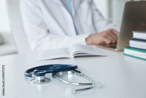 Doctor at white table in hospital, focus on medical stethoscope