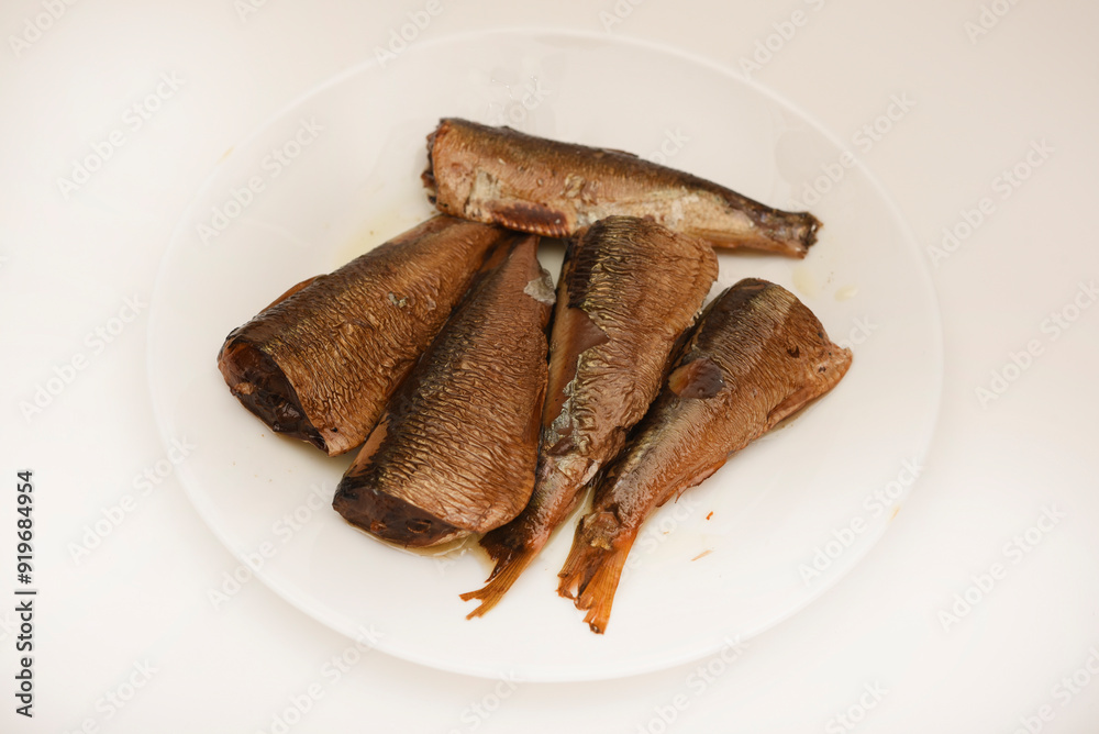Sprats on a white plate. Canned fish in oil. Fish appetizer. Sprats on a white plate. Canned fish in oil. Fish appetizer.