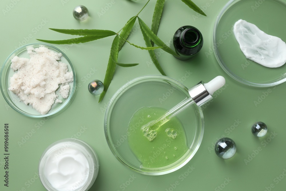 Petri dishes with cosmetic products, pipette and leaves on green background, flat lay Petri dishes with cosmetic products, pipette and leaves on green background, flat lay