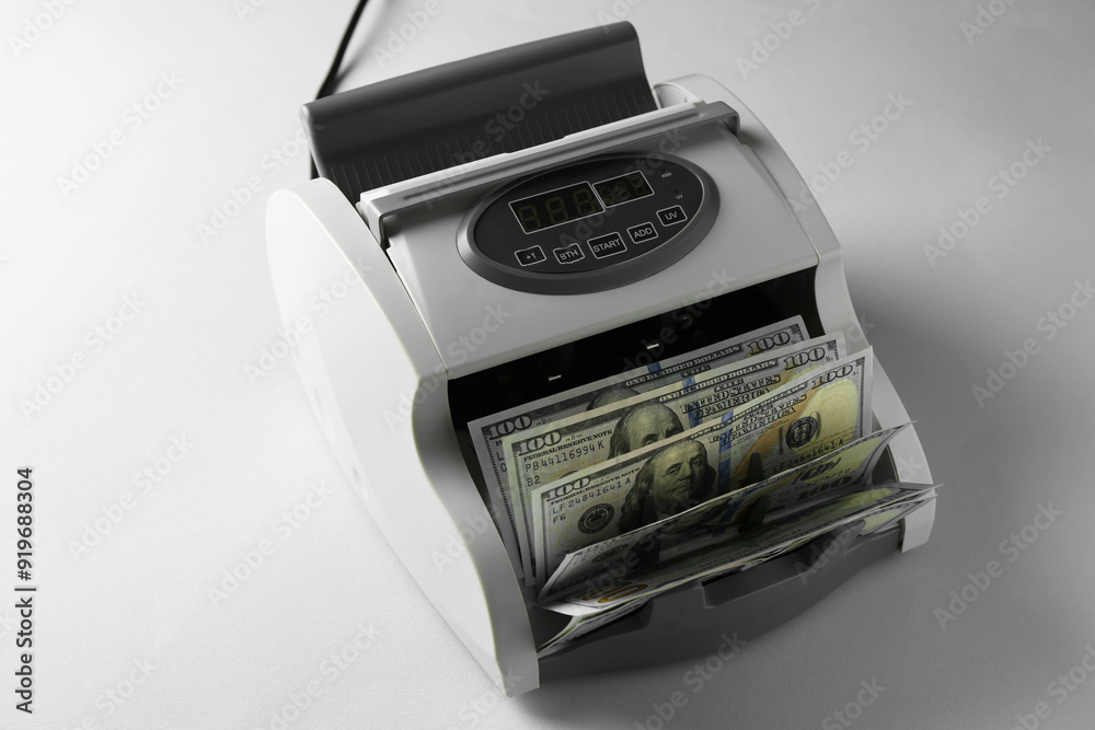 Money counter machine with dollar banknotes on light table, above view Money counter machine with dollar banknotes on light table, above view